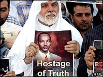 A protestor holds up a poster featuring Sami al-Haj