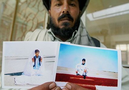 A relative of Mohamed Jawad holds up photos of Jawad, taken shortly before his capture