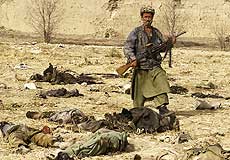 A Northern Alliance soldier poses by corpses after the Qala-i-Janghi massacre, December 2001